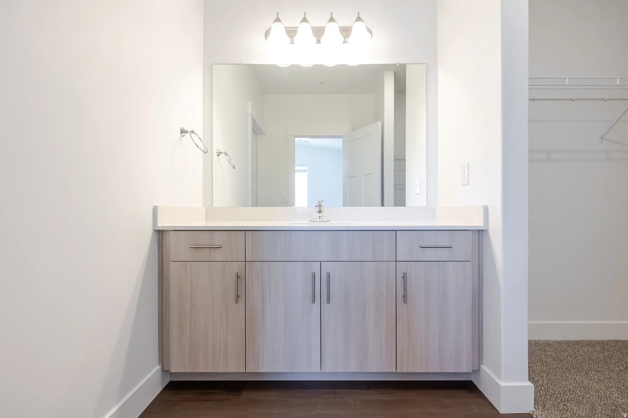 Single vanity with light wood-finish cabinetry, white countertop, and a rectangular mirror