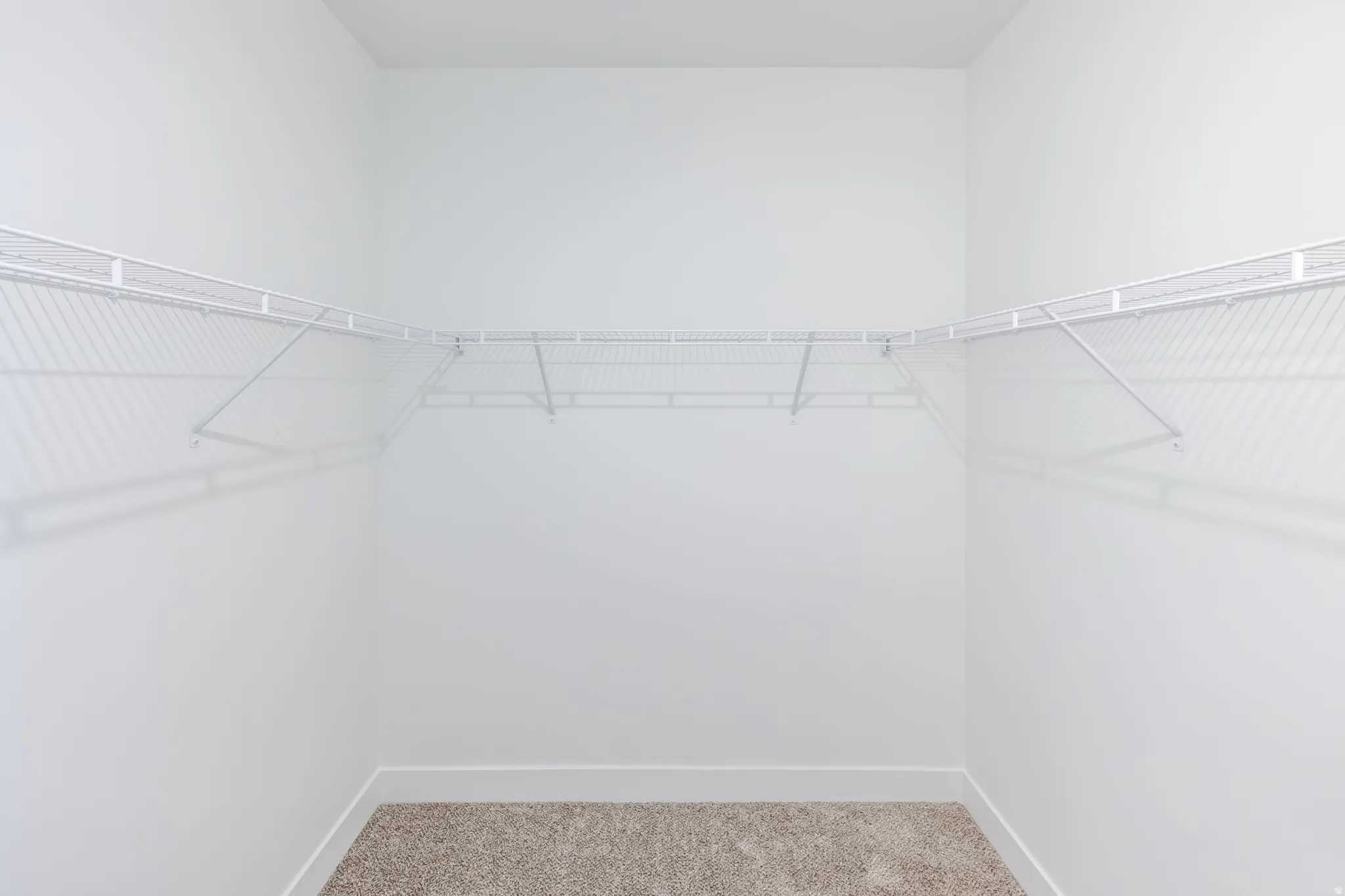 Built-in wire shelving system, light neutral wall color, and carpeted flooring