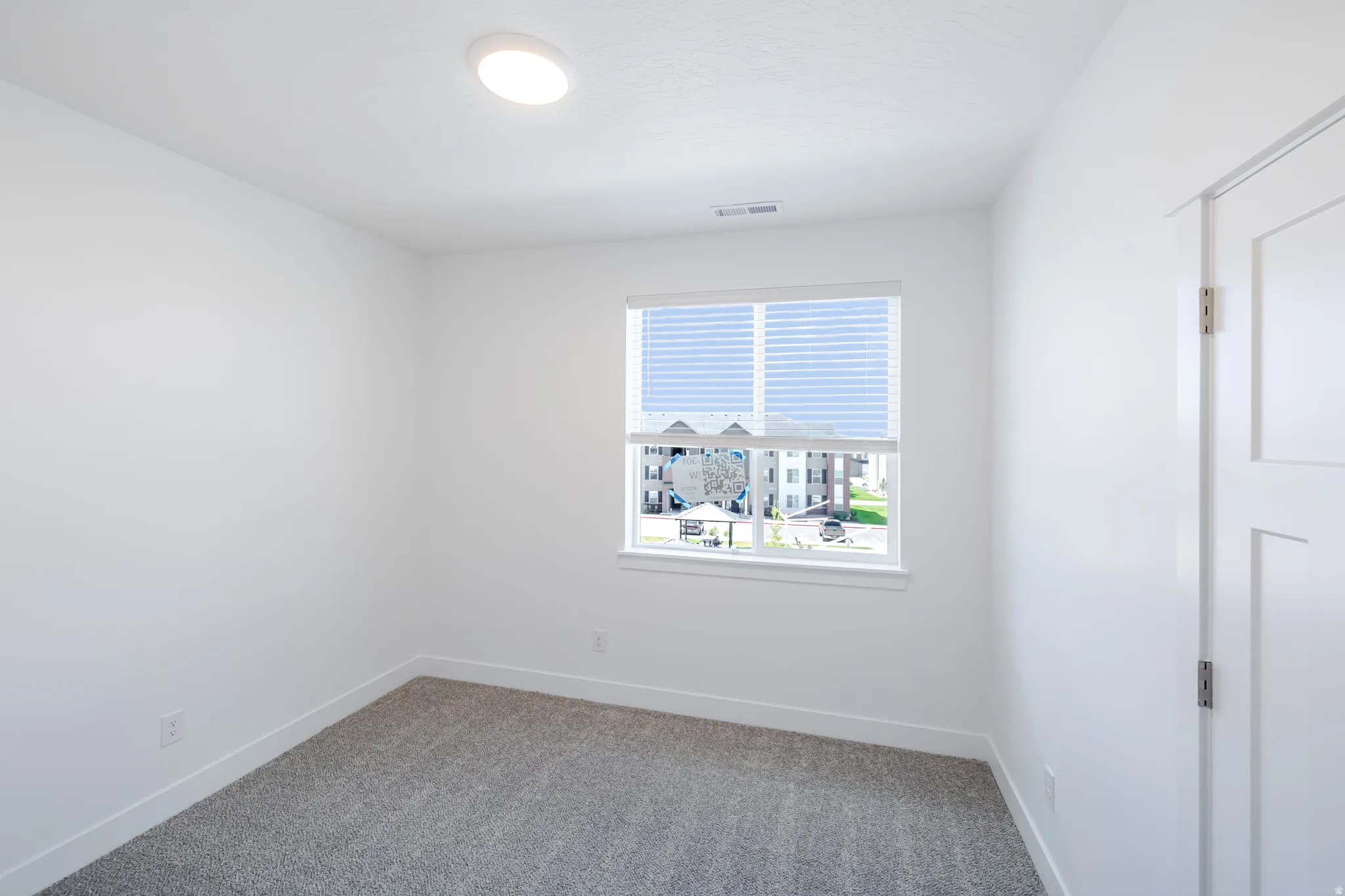 Recessed ceiling lighting, window with blinds, panel door, and carpeted flooring