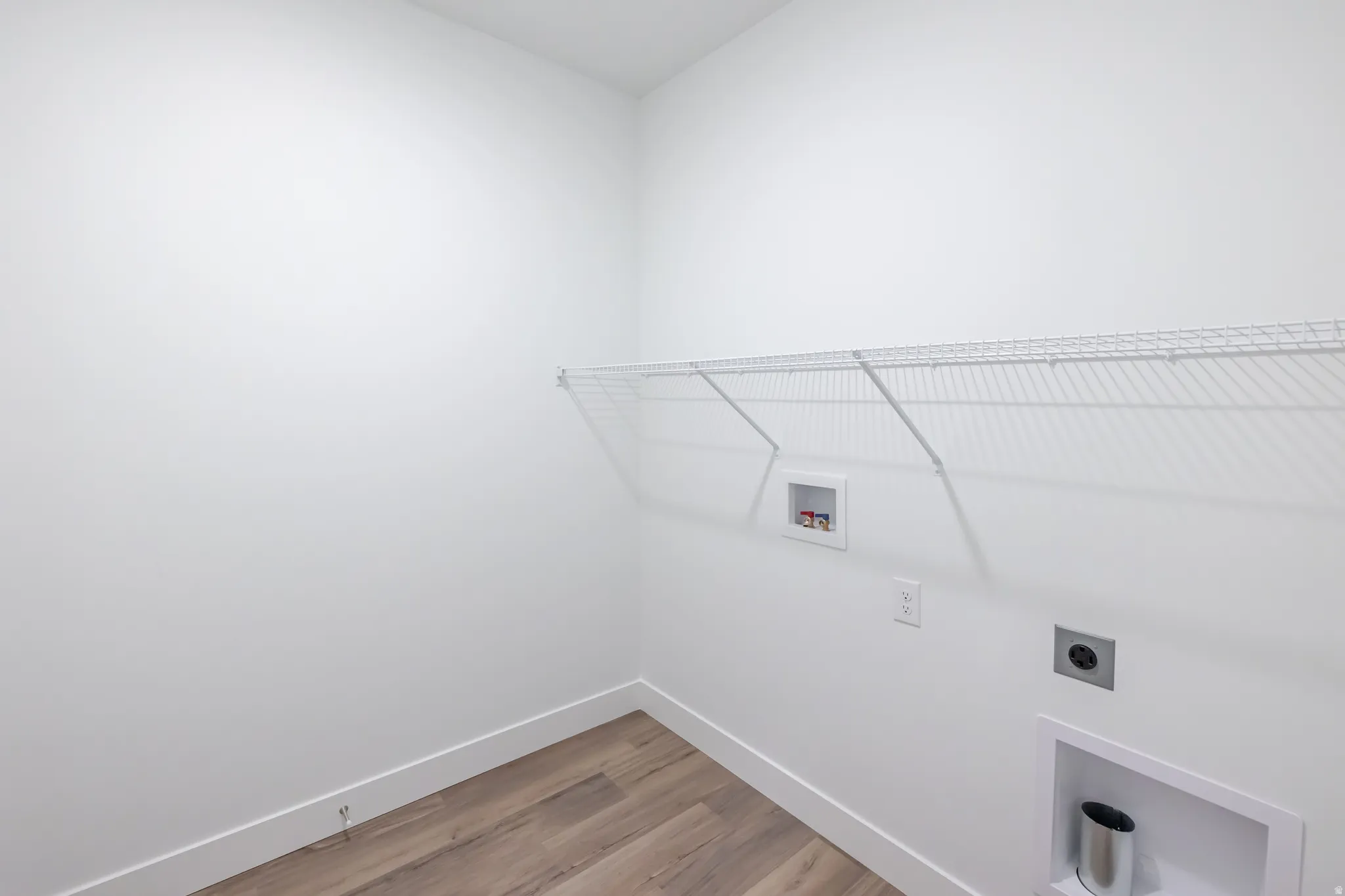 Laundry area with wood-finish flooring and a wire storage shelf
