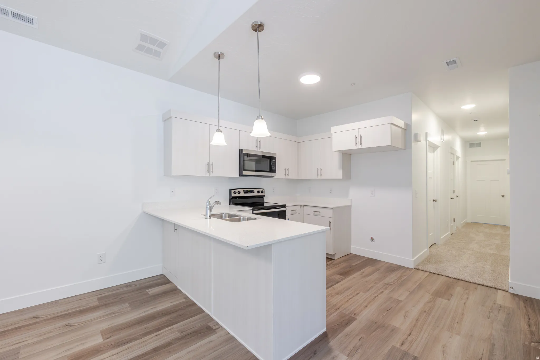 Kitchen featuring white shaker-style cabinetry, stainless steel appliances, and a double basin sink
