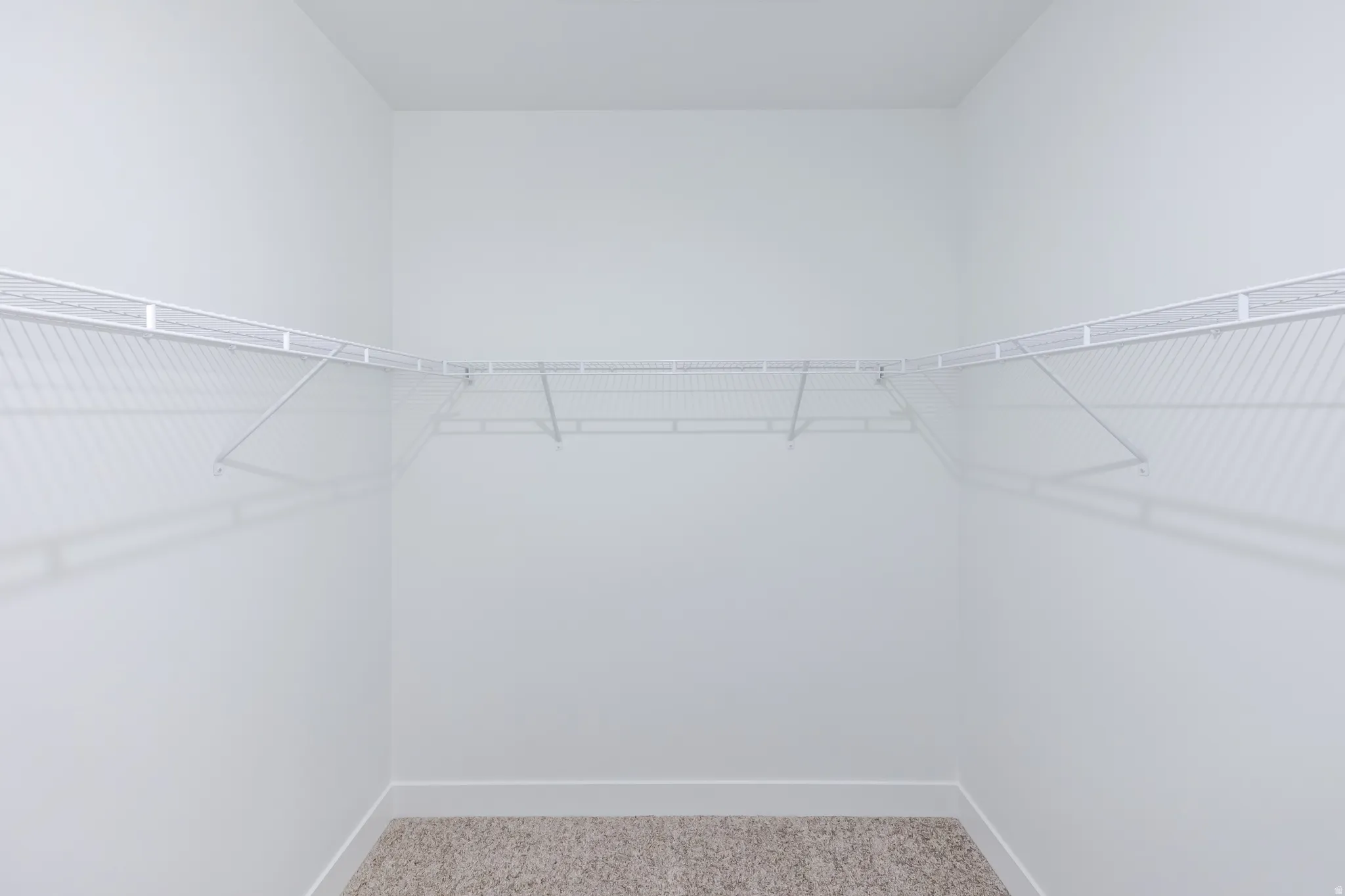 Integrated wire shelving system with white finish, installed against light-colored walls and complemented by neutral-toned carpeting