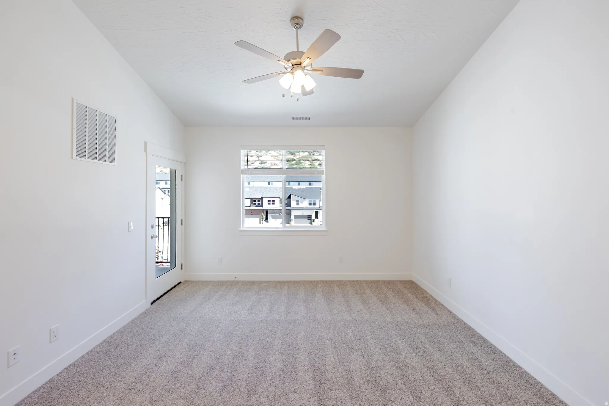 Plush carpet flooring, white walls, and a ceiling fan with integrated lighting