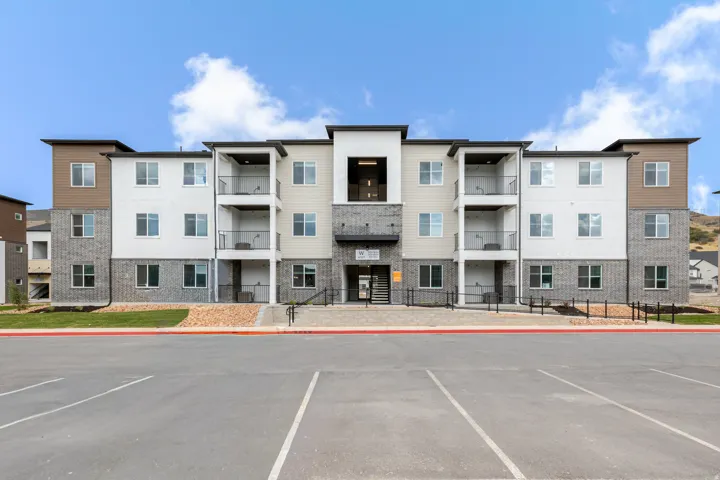 Multi-story building featuring a facade of white and beige siding with stone veneer accents