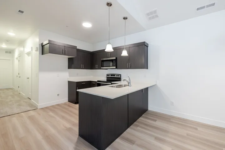 Kitchen featuring dark wood-finish cabinetry, light countertops, and stainless steel appliances