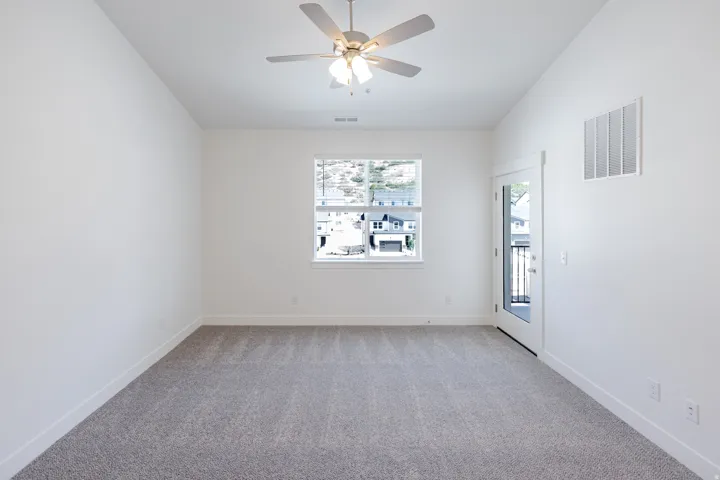Recessed window, ceiling fan, carpet flooring, and a glass-paneled door opening to an outdoor balcony