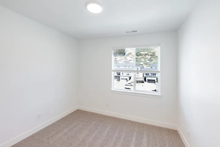Neutral carpet flooring, recessed ceiling light, and clean white walls
