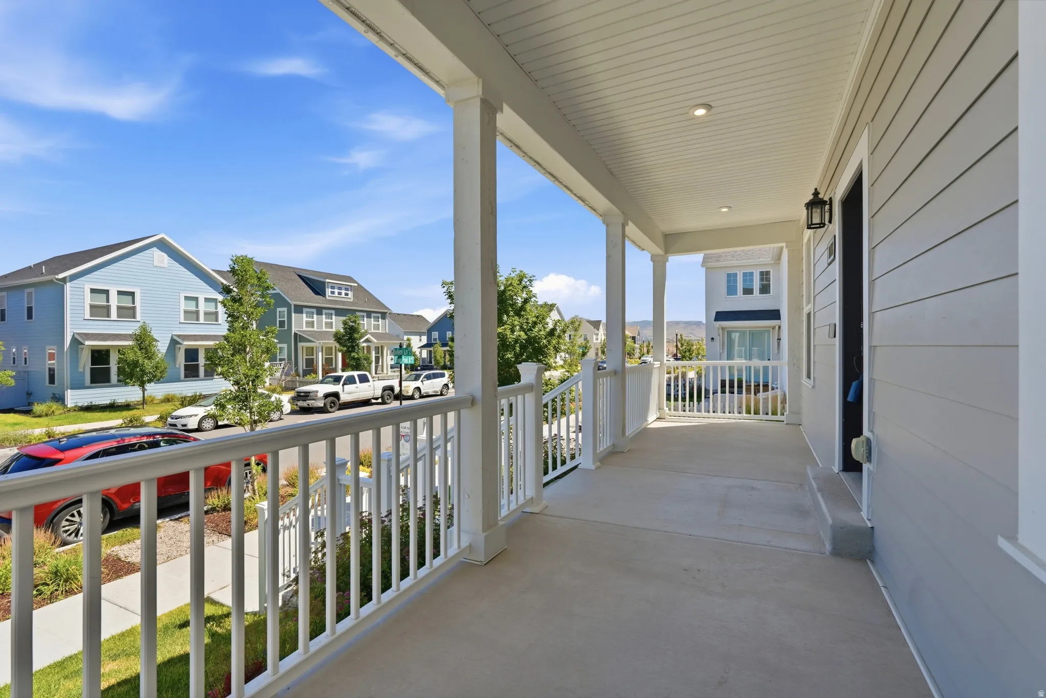 Covered front porch with white railings, white columns, recessed lighting, and a dark exterior light fixture