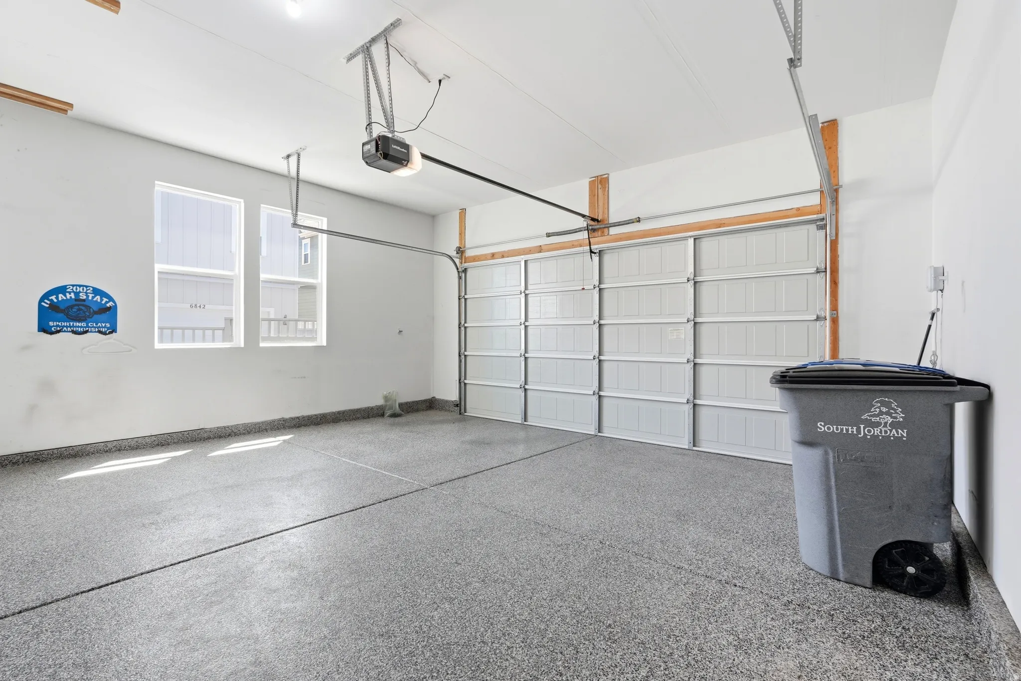 Attached garage featuring an epoxy-coated floor, automatic garage door opener, and two windows providing natural light