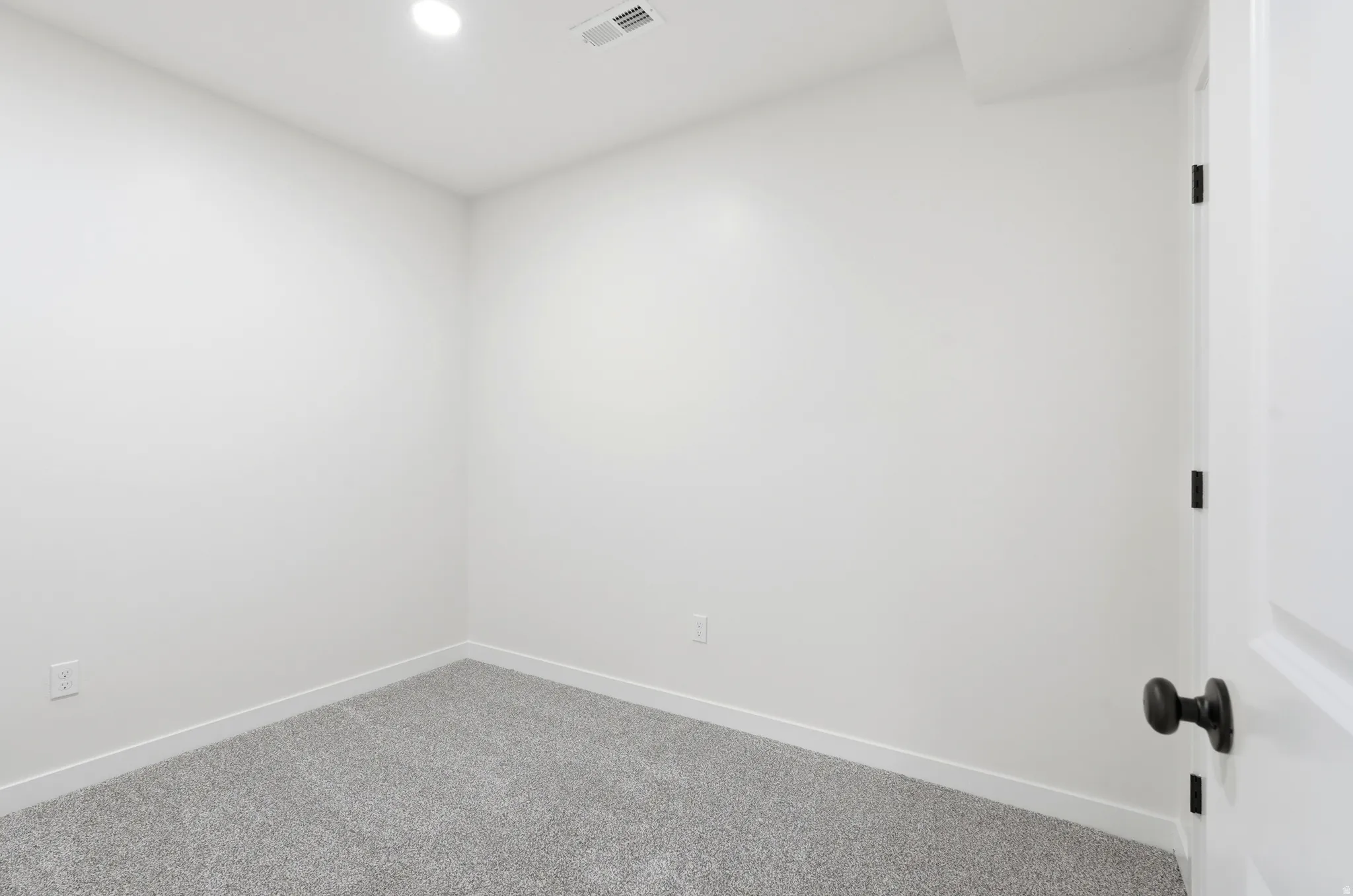 Bright room featuring light gray carpet, white baseboards, and recessed ceiling lighting