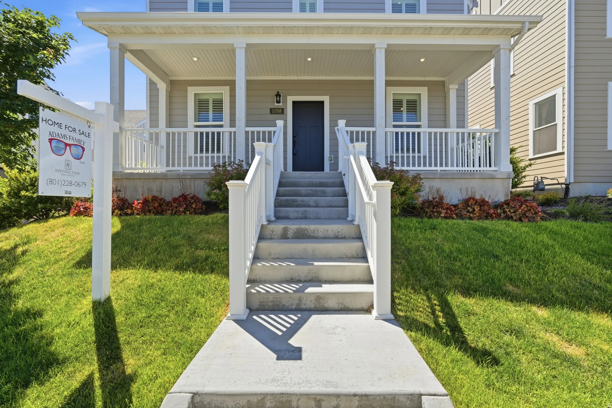 Inviting front porch with white railings and columns, featuring a dark blue entry door
