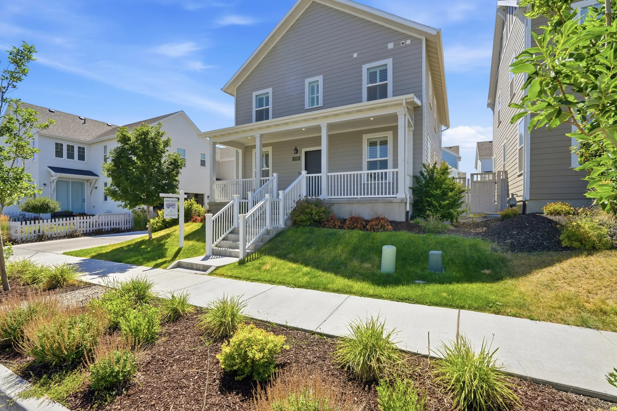 Two-story residence featuring light gray siding with white trim and a covered front porch