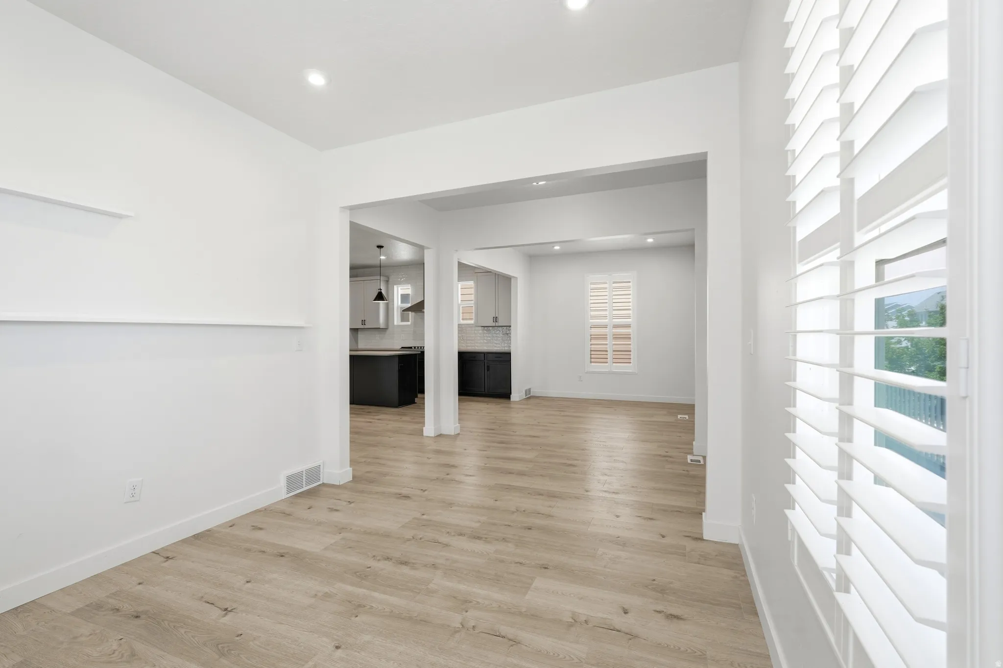Open-concept interior featuring light wood-finish flooring, white walls, and recessed lighting