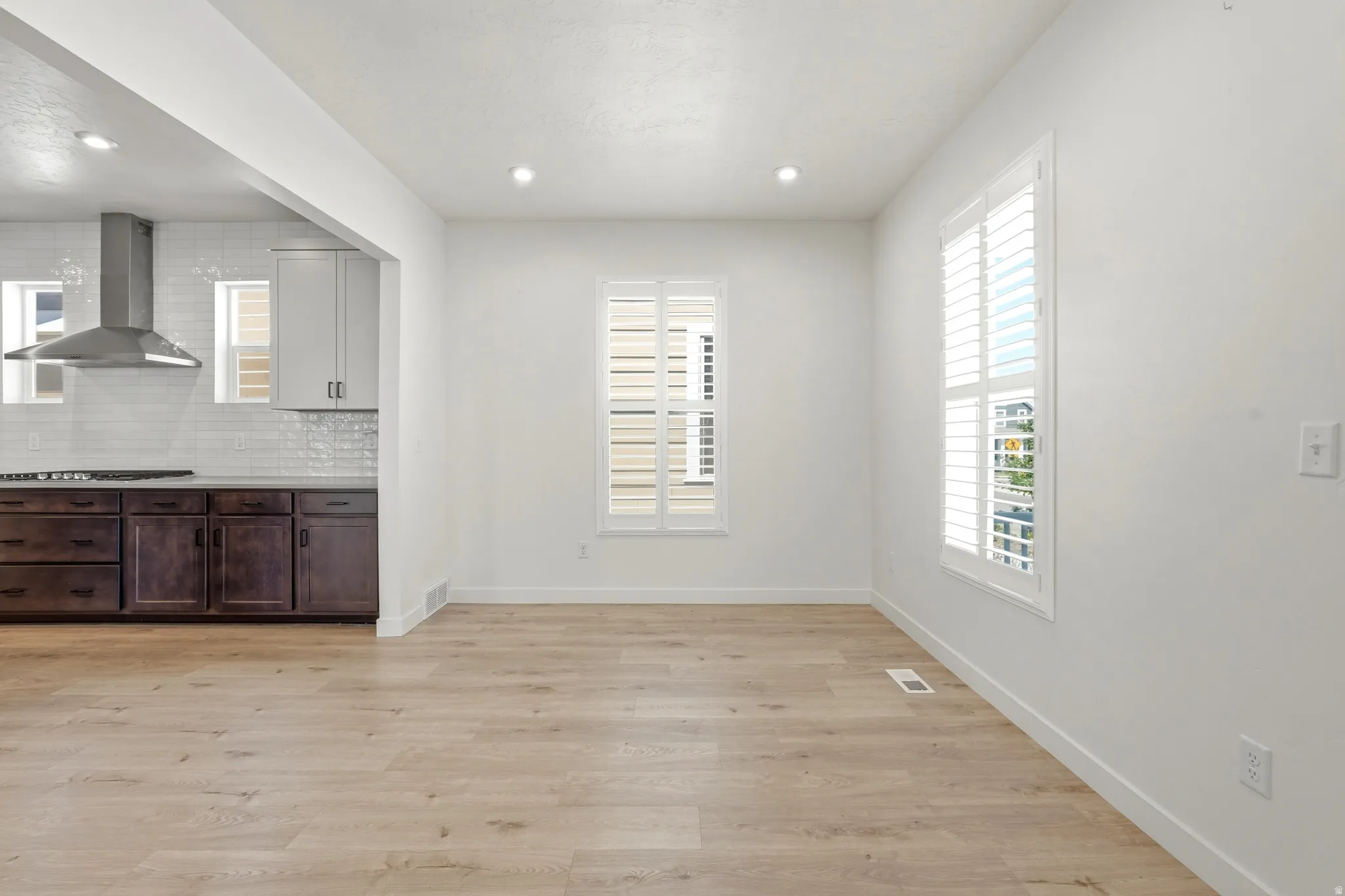 Open-concept living area featuring light wood-finish flooring and bright white walls