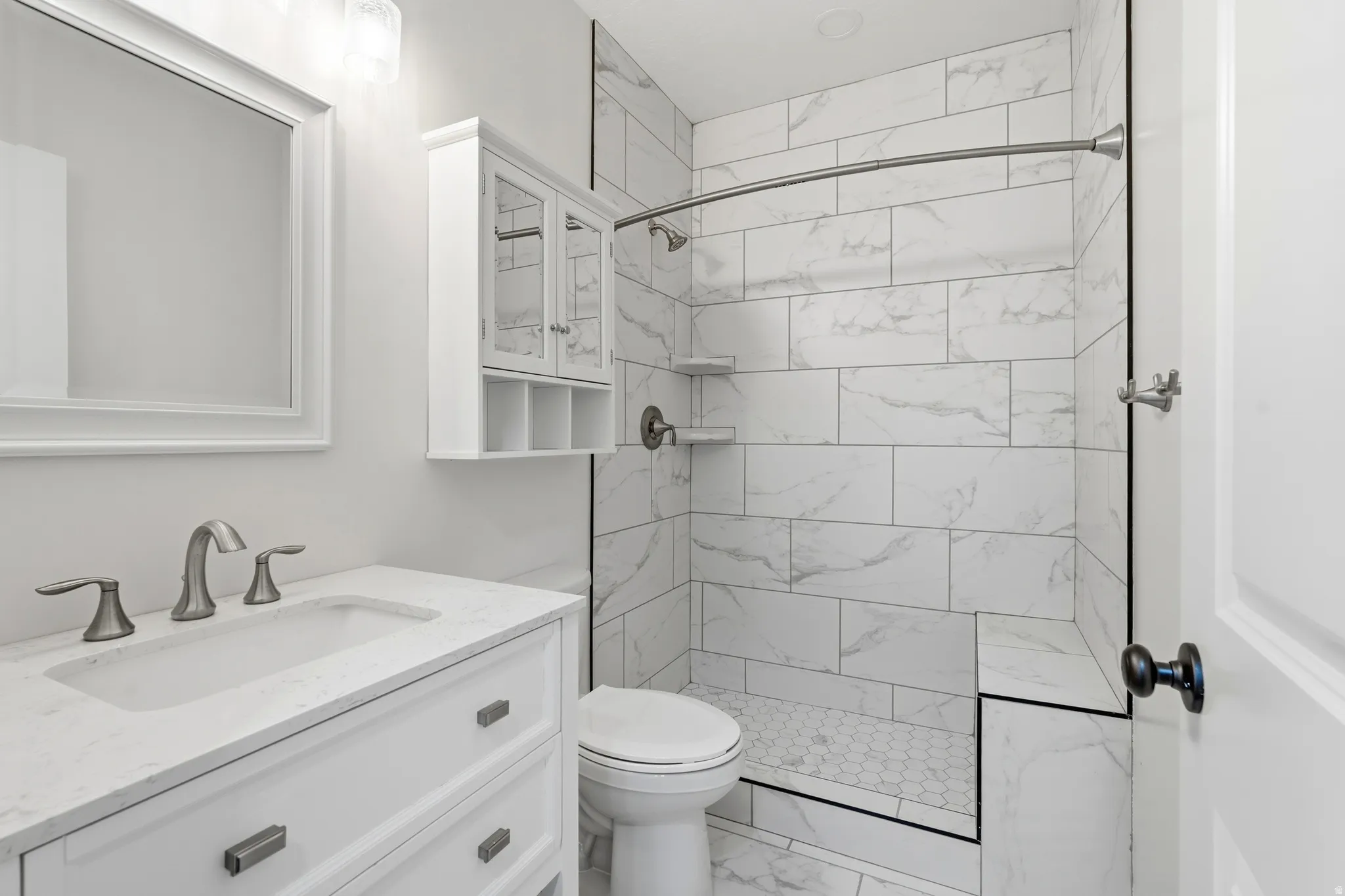 Bathroom featuring a white vanity with an integrated sink, brushed nickel faucet, and a framed mirror