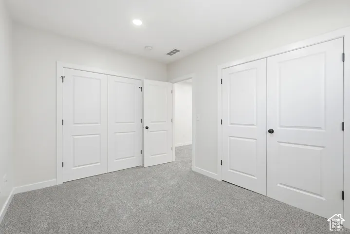 Room featuring light gray carpeting, crisp white walls, and bright recessed lighting