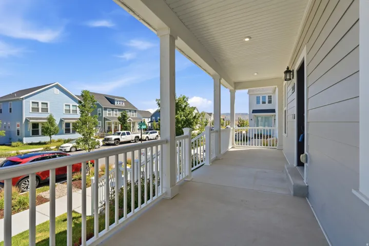 Covered front porch with white railings, white columns, recessed lighting, and a dark exterior light fixture