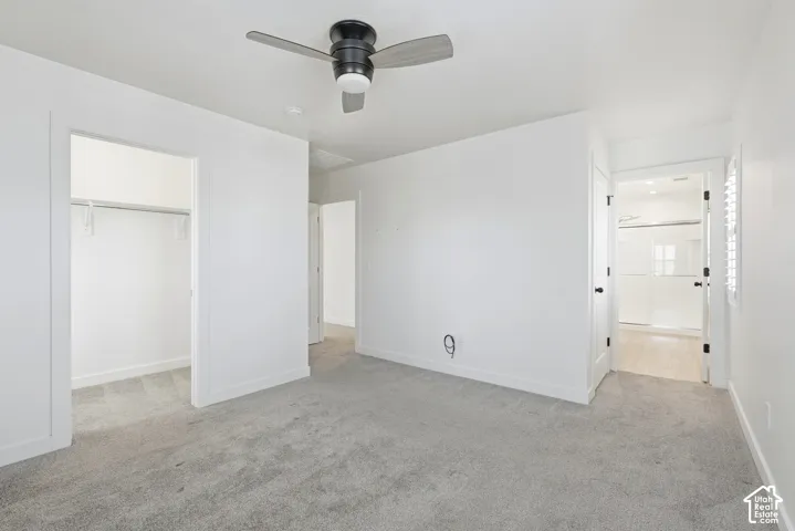Spacious room featuring light grey carpet, a modern ceiling fan, and crisp white walls