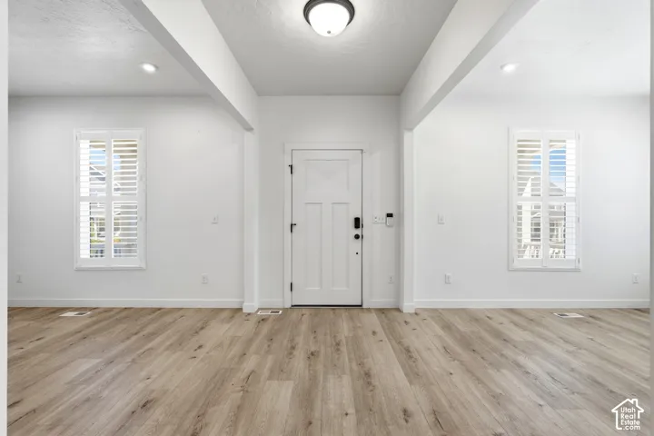 Entryway featuring a panel door with smart lock technology, wood-finish flooring, two large windows with plantation shutters, recessed ceiling lighting, and a flush mount fixture