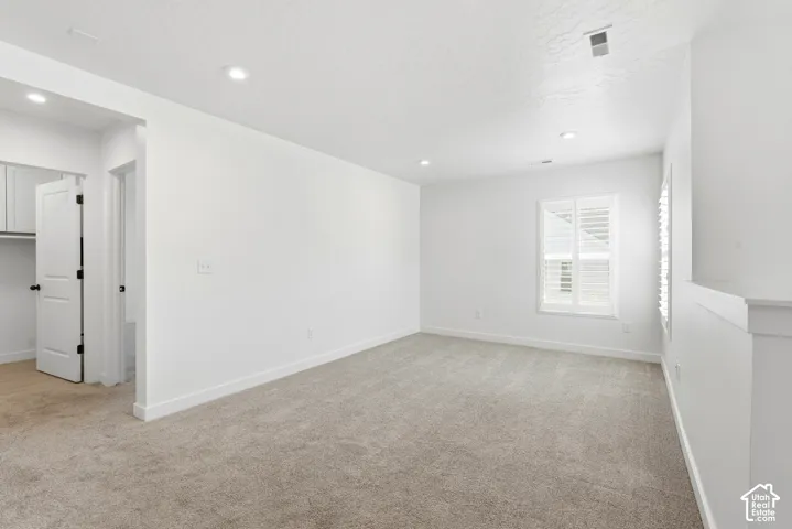 Carpeted room with recessed lighting and a window featuring white plantation shutters