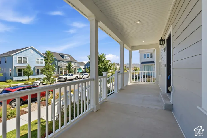 Covered front porch with white railings, white columns, recessed lighting, and a dark exterior light fixture