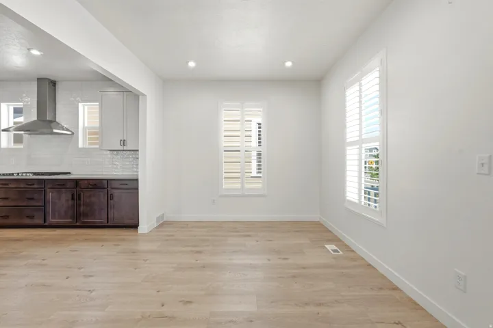 Open-concept living area featuring light wood-finish flooring and bright white walls