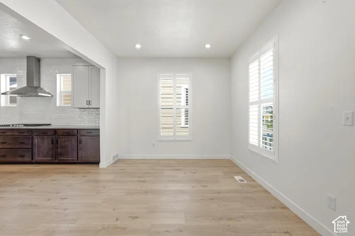 Open-concept living area featuring light wood-finish flooring and bright white walls