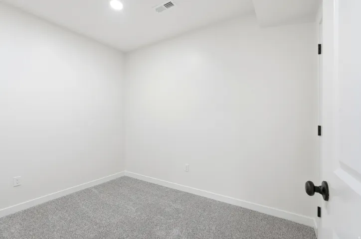 Bright room featuring light gray carpet, white baseboards, and recessed ceiling lighting