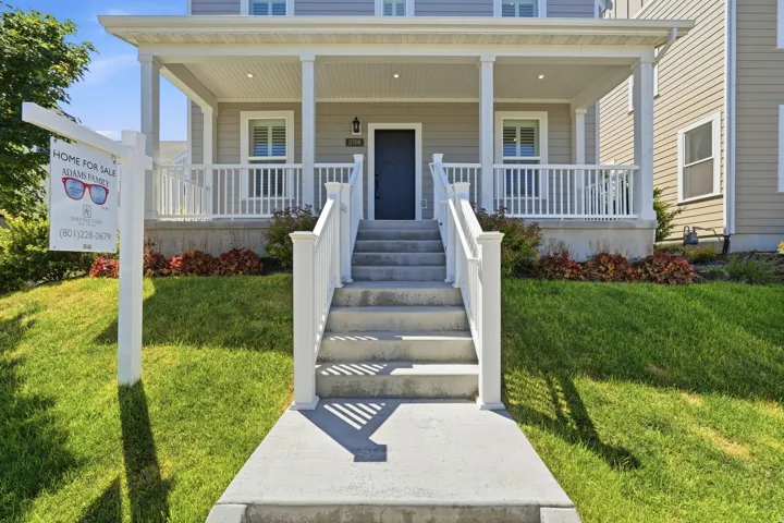 Inviting front porch with white railings and columns, featuring a dark blue entry door