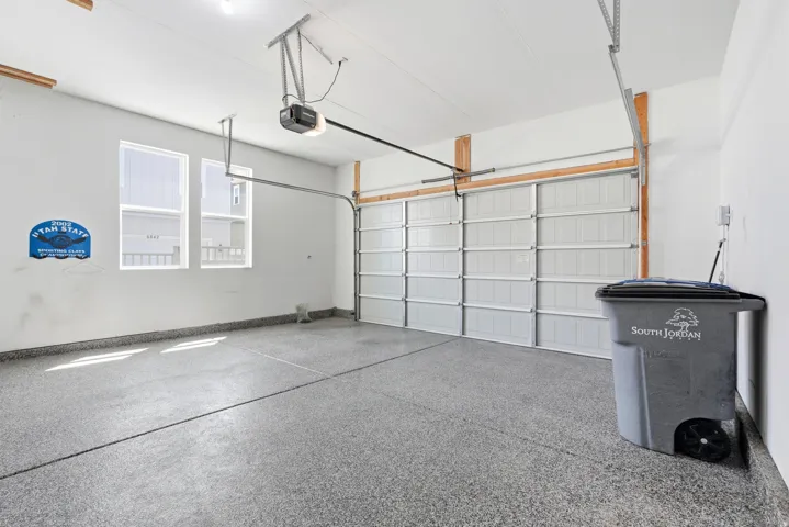 Attached garage featuring an epoxy-coated floor, automatic garage door opener, and two windows providing natural light