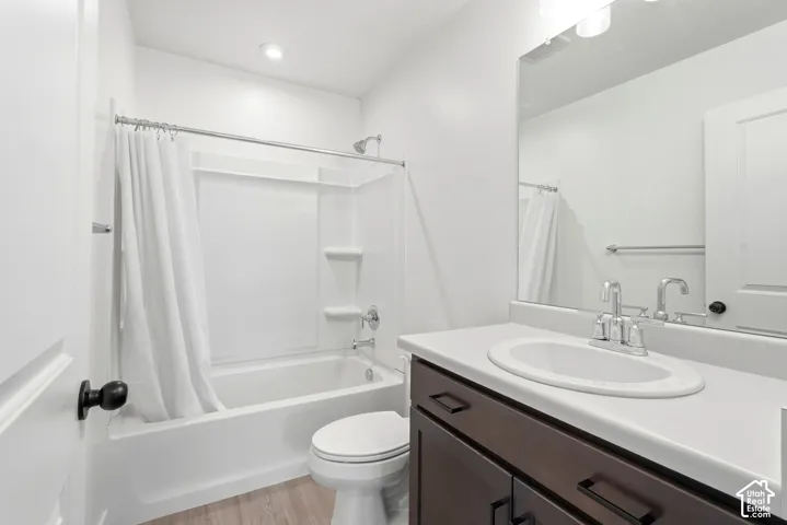 Bathroom featuring a white tub/shower combination, dark wood-finish vanity with a light-colored countertop, and a large wall-mounted mirror