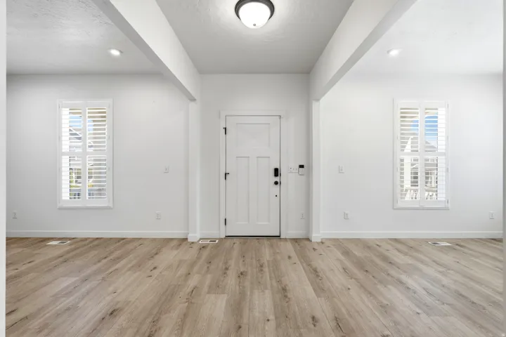 Entryway featuring a panel door with smart lock technology, wood-finish flooring, two large windows with plantation shutters, recessed ceiling lighting, and a flush mount fixture