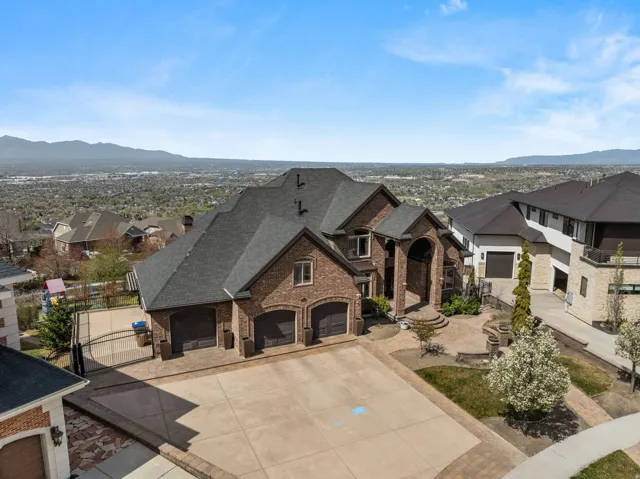 View of front of house featuring a mountain view, brick siding, a shingled roof, concrete driveway, and a gate