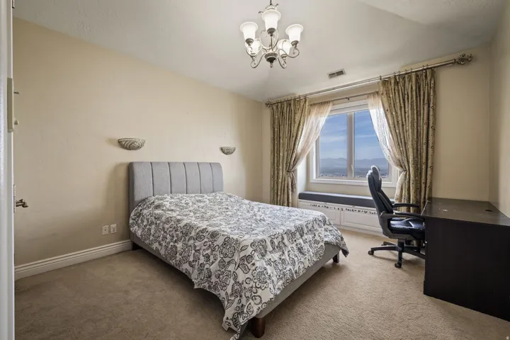 Carpeted bedroom featuring an office area and suspended lighting
