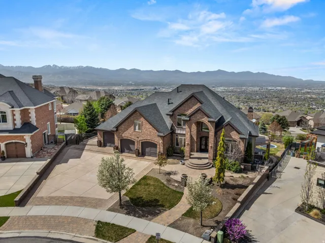 French provincial home featuring concrete driveway, a gate, brick siding, and a residential view