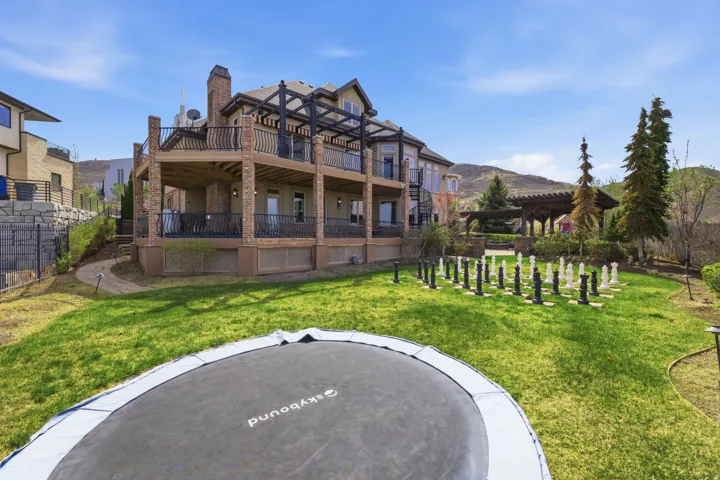 Back of property with a trampoline, a yard, a chimney, and brick siding