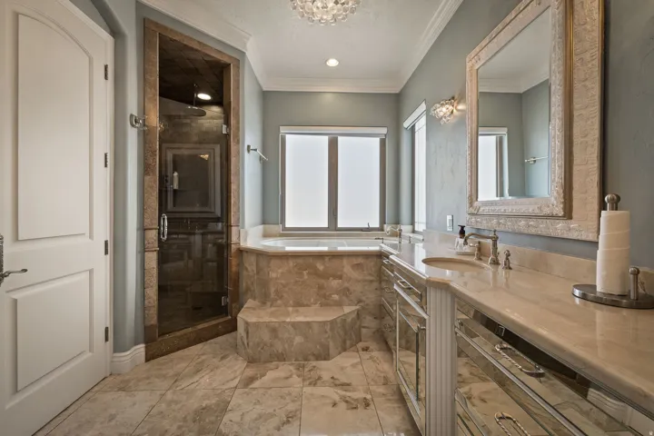Bathroom featuring crown molding, vanity, a stall shower, a garden tub, and suspended lighting