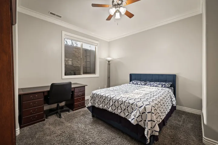 Bedroom featuring crown molding, dark colored carpet, a desk, and ceiling fan