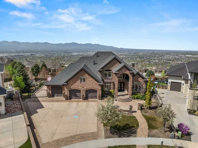 French country style house with brick siding, driveway, a mountain view, a residential view, and an attached garage