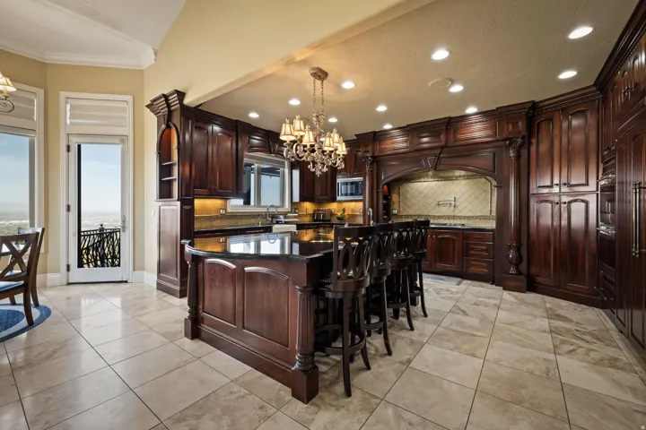 Kitchen featuring a chandelier, a center island, backsplash, and dark stone countertops
