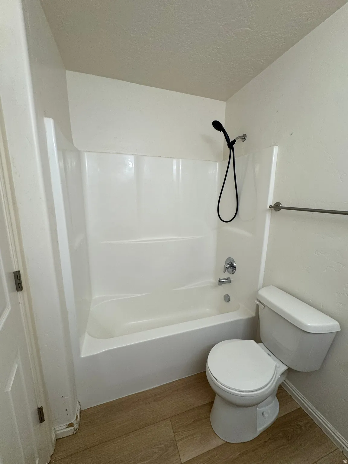 Bathroom featuring a textured ceiling, wood finished floors, and shower / washtub combination
