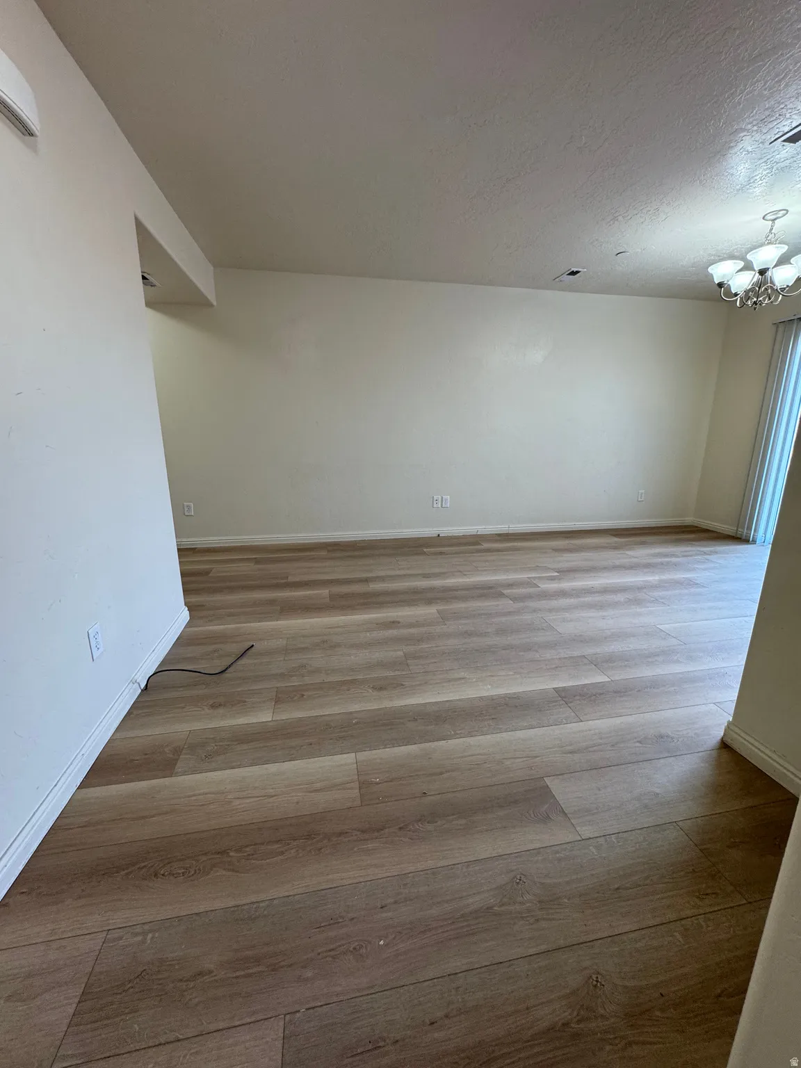 Empty room featuring light wood finished floors and hanging lights