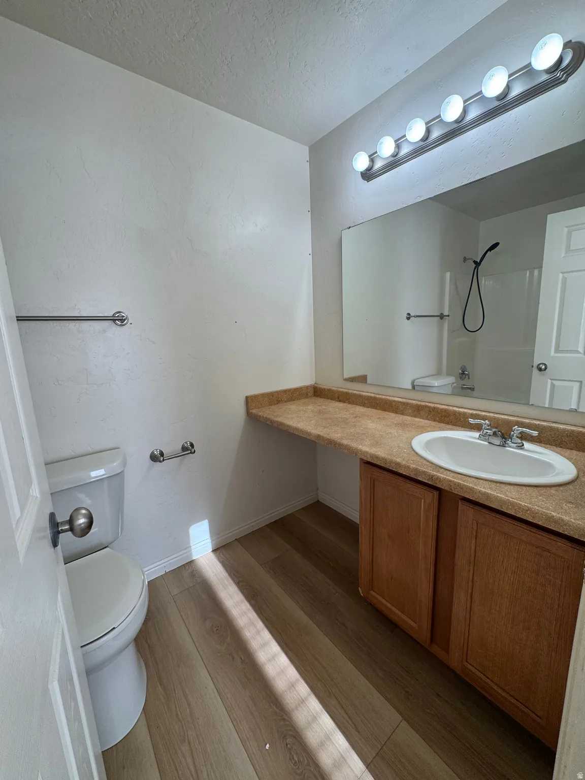 Bathroom with vanity, light wood-style floors, a textured ceiling, and shower / washtub combination