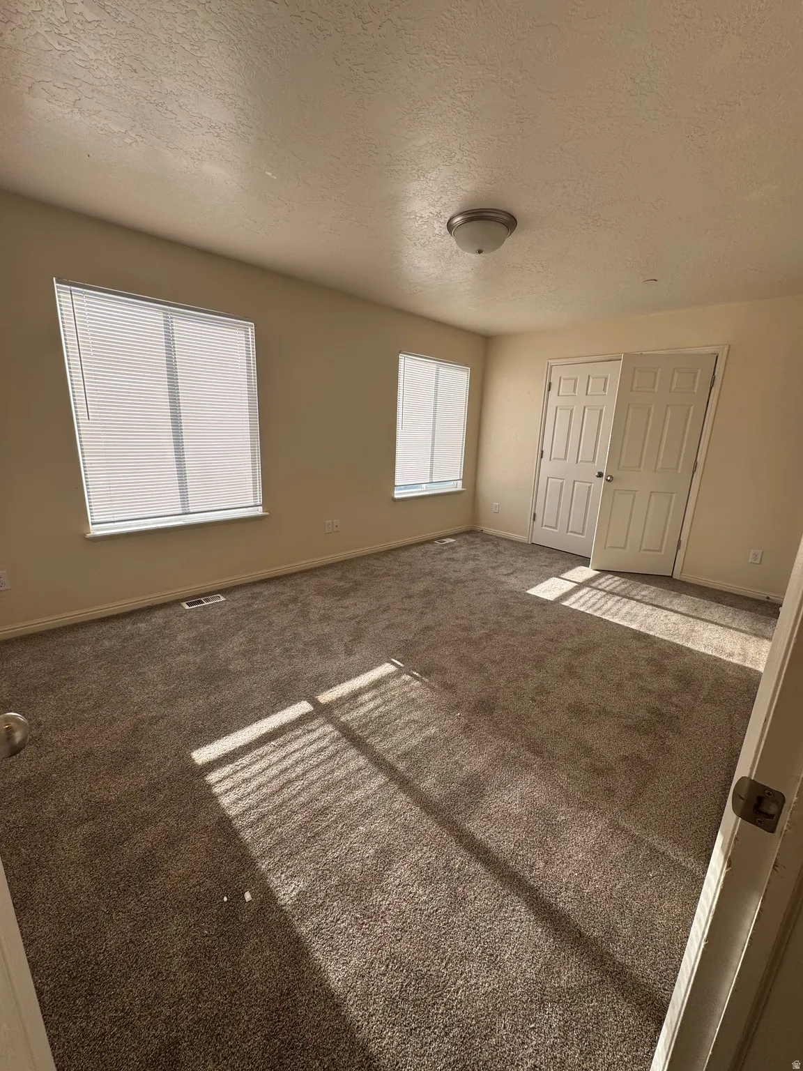 Unfurnished bedroom with a textured ceiling and carpet