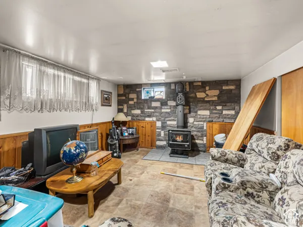 Living area featuring wood walls, a wainscoted wall, and a wood stove