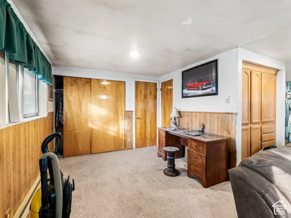 Office space with wooden walls, light colored carpet, a baseboard heating unit, and wainscoting