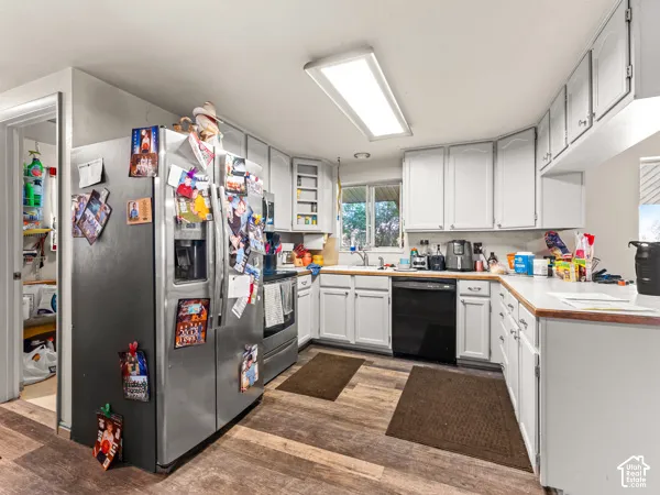 Kitchen featuring stainless steel appliances, light countertops, dark wood finished floors, and white cabinetry