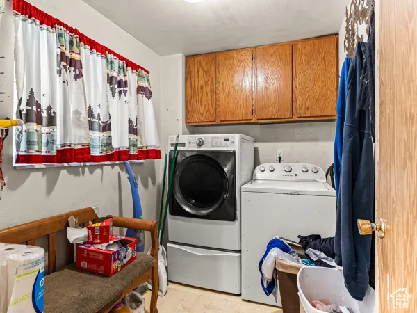 Laundry room with light flooring, washing machine and dryer, and cabinet space