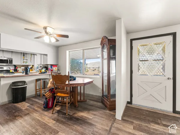Dining space with ceiling fan and dark wood-style flooring