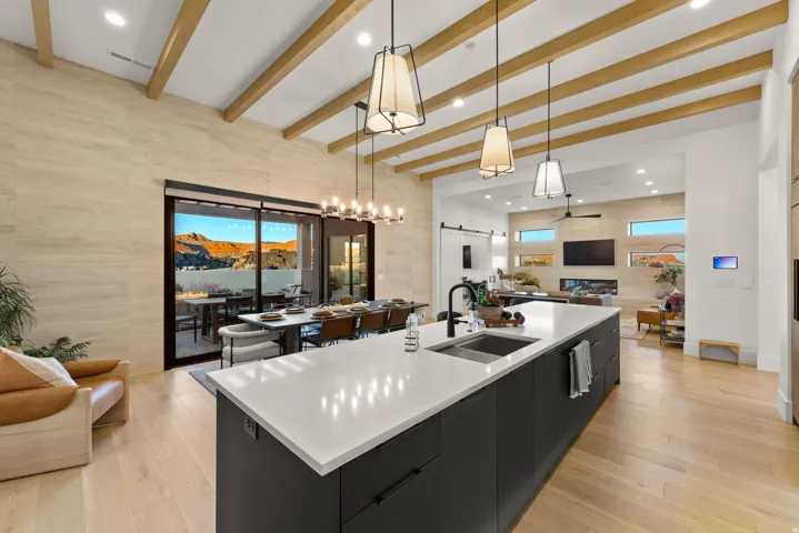 Kitchen featuring open floor plan, a barn door, a large island with sink, dark cabinets, and light wood-style floors